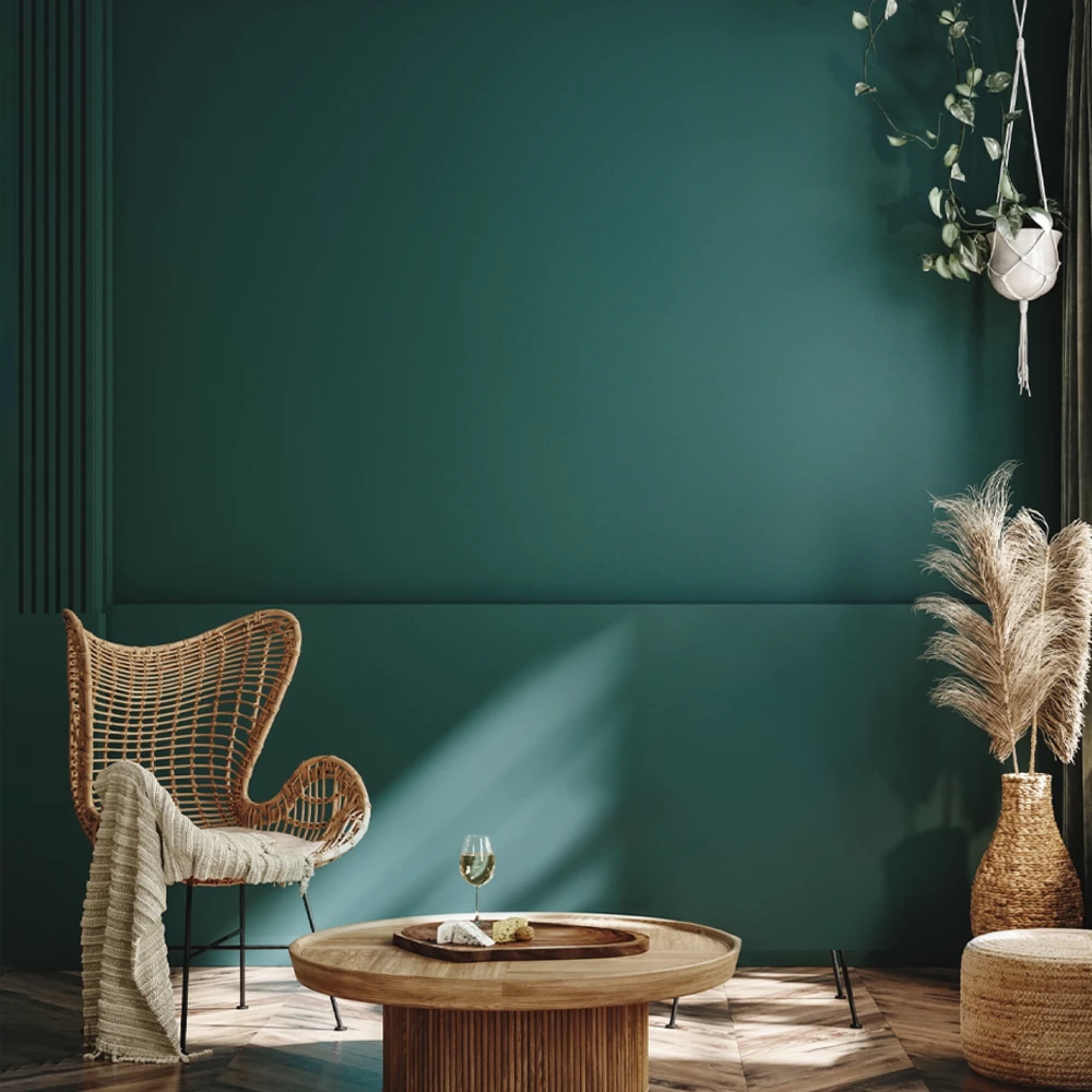 Deep teal-green feature wall with a rattan chair and hanging plant